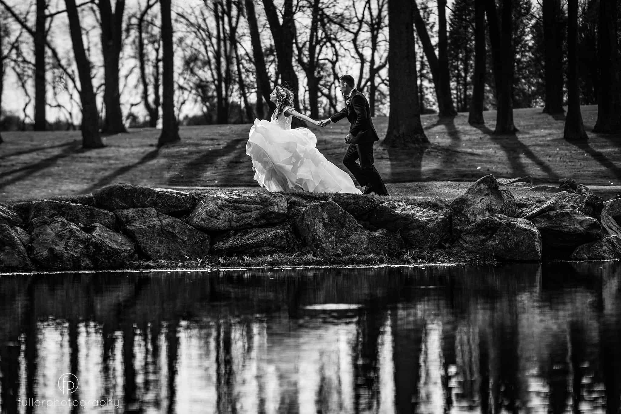 bride pulling groom along the water at Penn Oaks