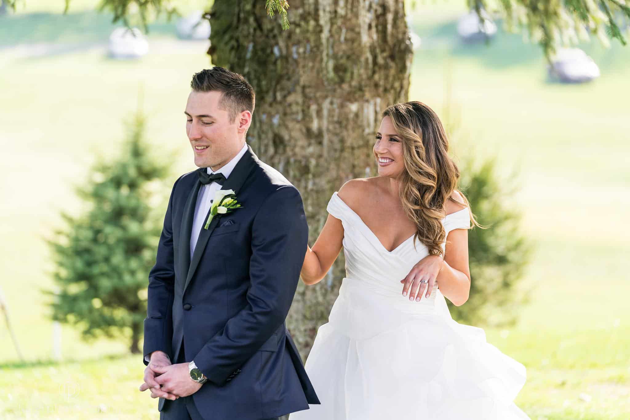 Bride sneaking up behind the groom during their first look at Penn Oaks