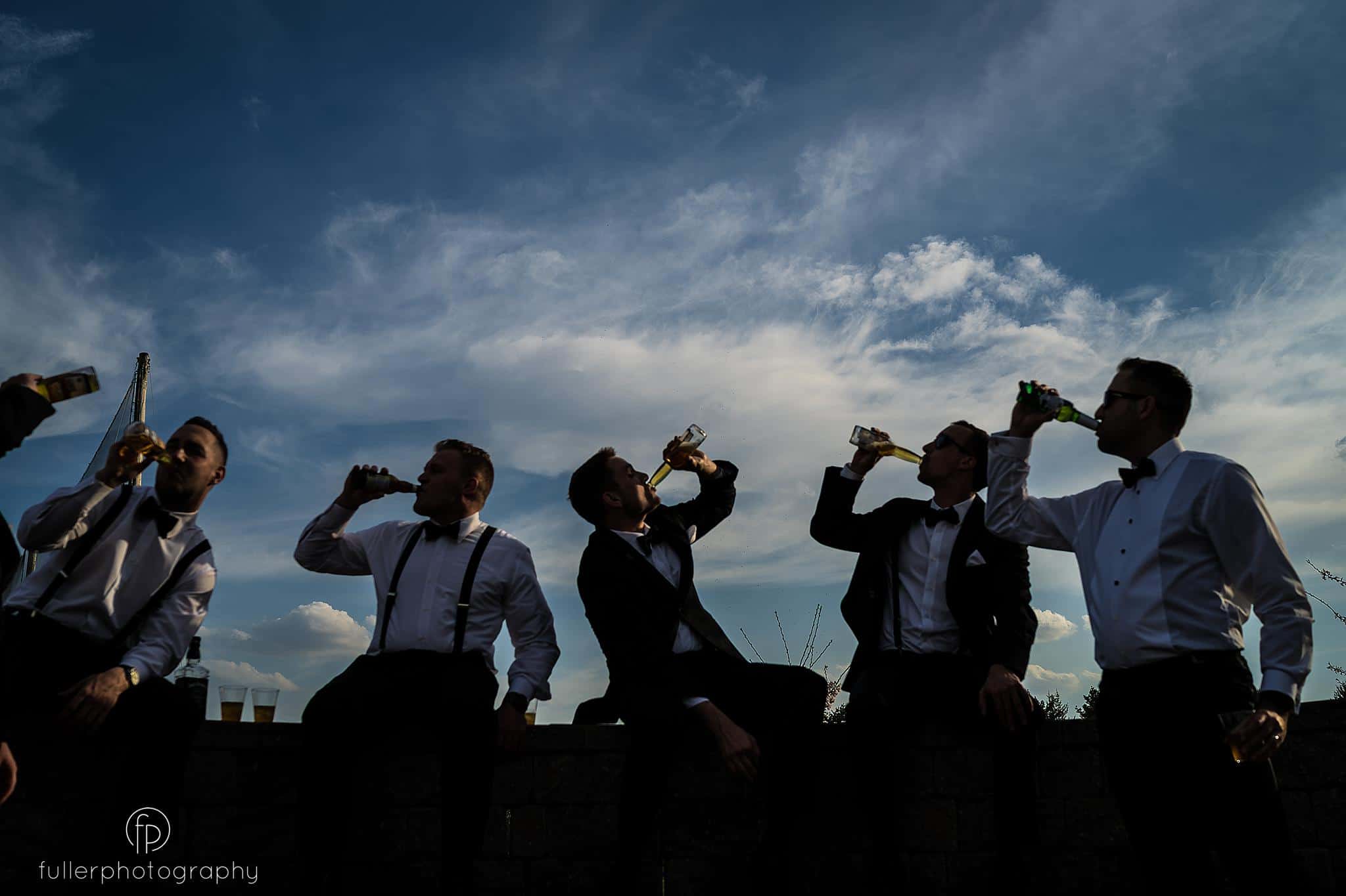 Groomsmen chugging their beer as a silhouette
