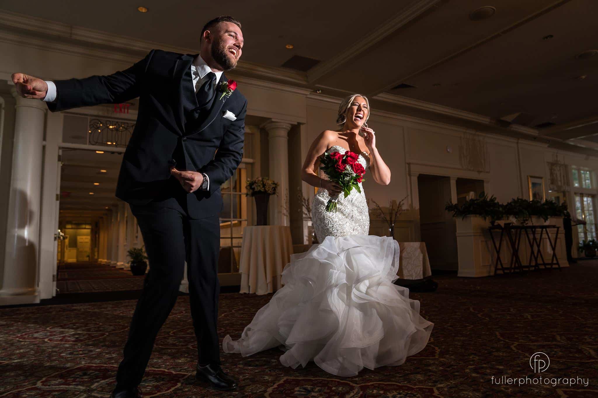 Groom and bride dancing and laughing as they enter the ballroom of the Deerfield Country Club