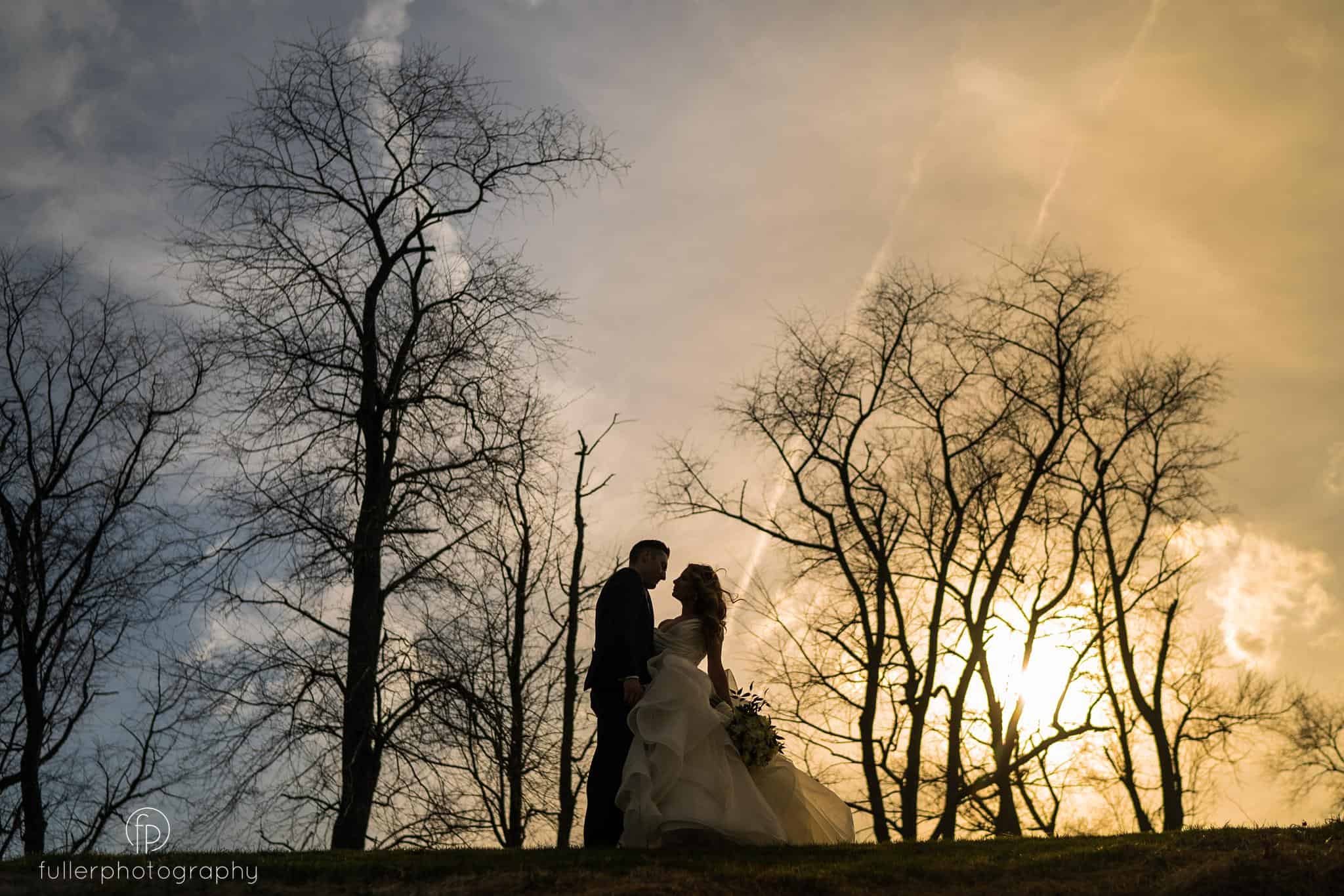 Bride and groom on hill during sunset