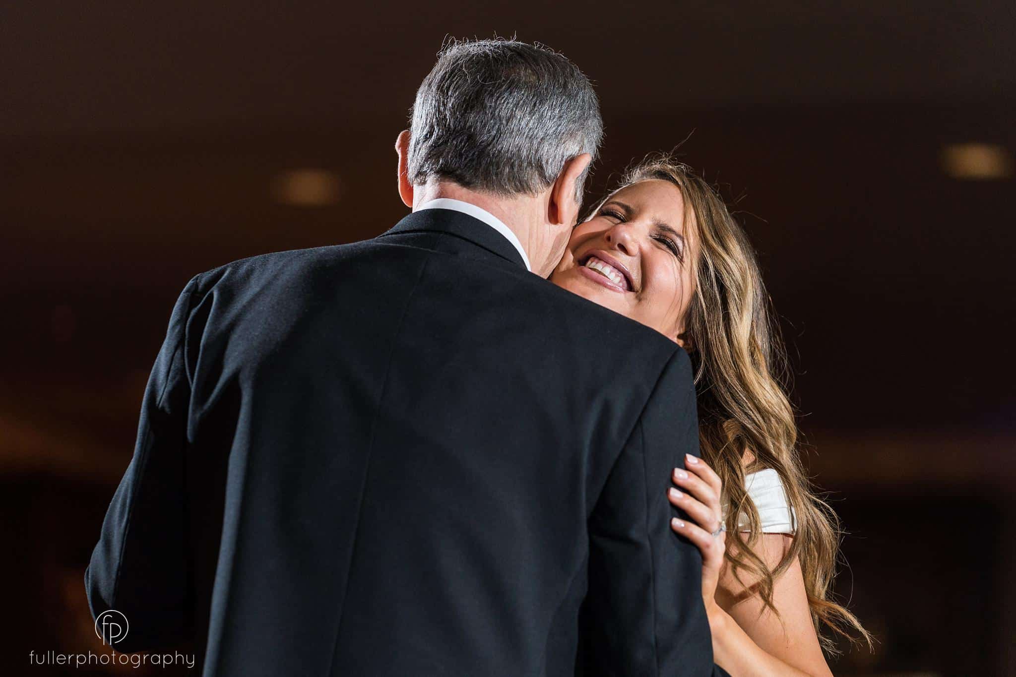 Bride smiling while hugging her dad on the dance floor at Penn Oaks