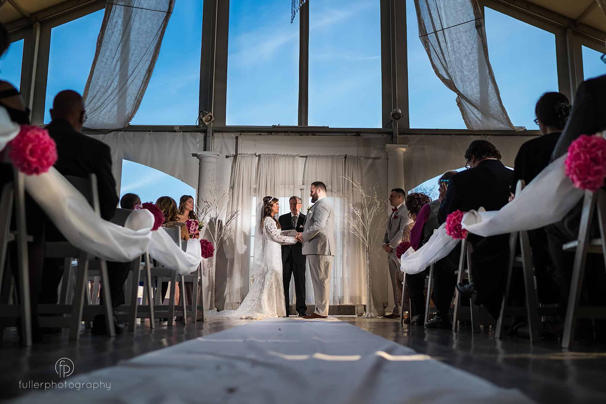 Bride and groom holding hands during the indoor ceremony at Penn Oaks