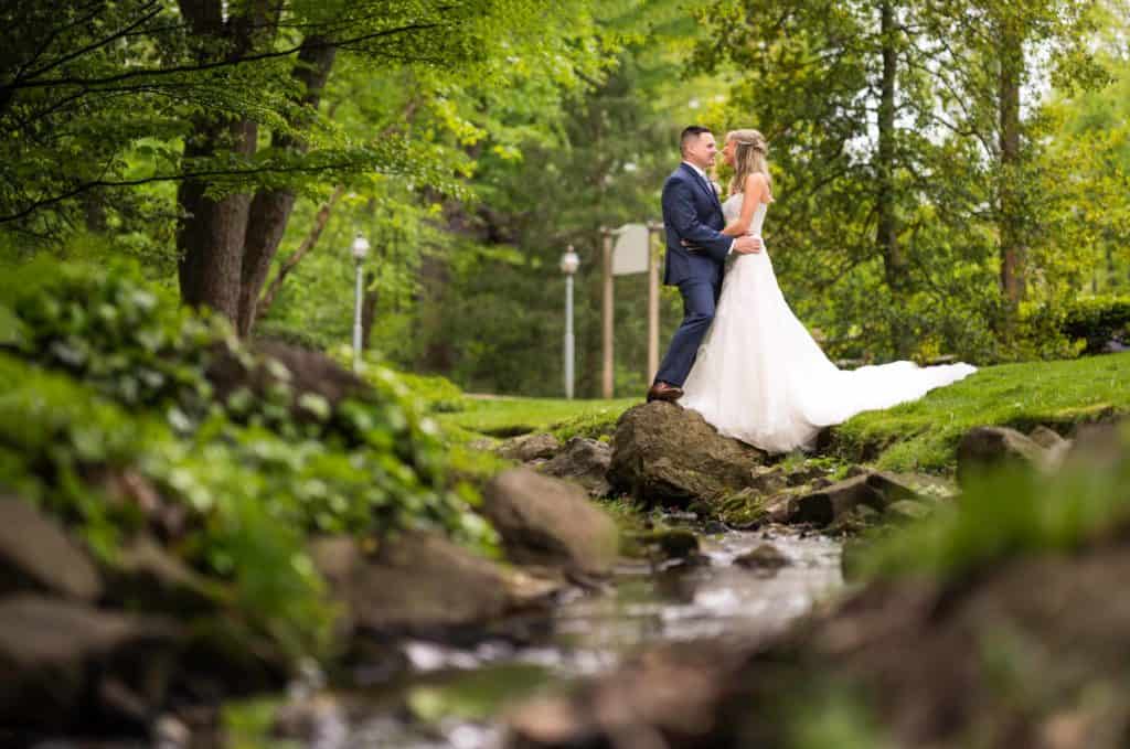 Bride and groom by the stream outside of Pomme Randor wedding