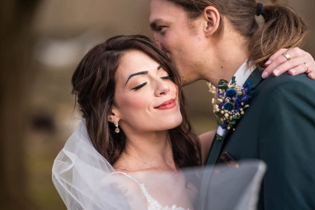 Groom kissing his wife on the head at their Durham Hill Farm